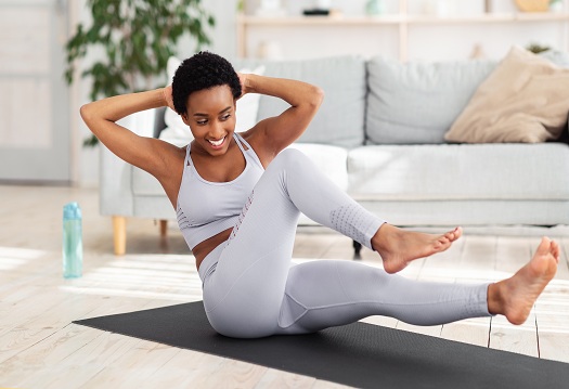 Young black woman exercising in her house gym, doing abs exercises, working out at home during coronavirus quarantine